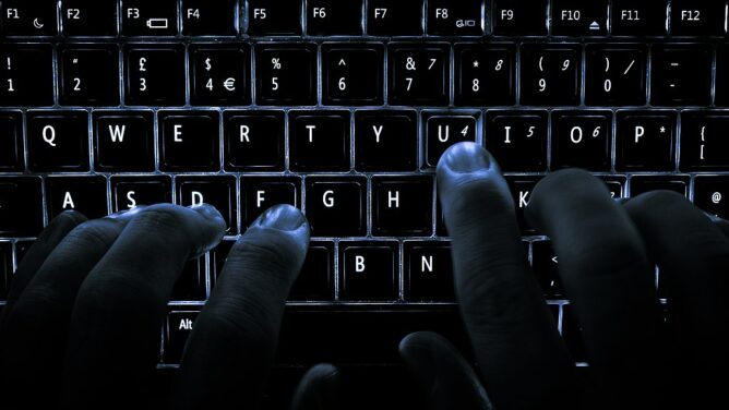 Photo of a backlit keyboard with a person typing